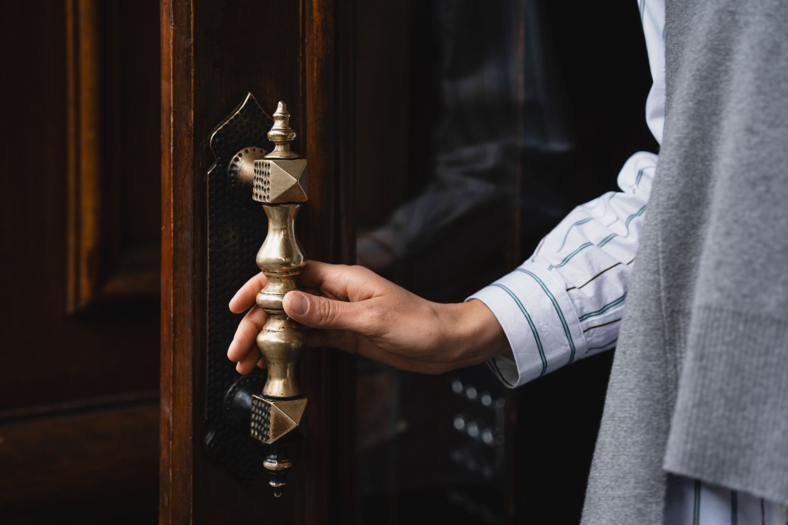 A hand on a cabinet handle, showing the wear pattern a finish develops