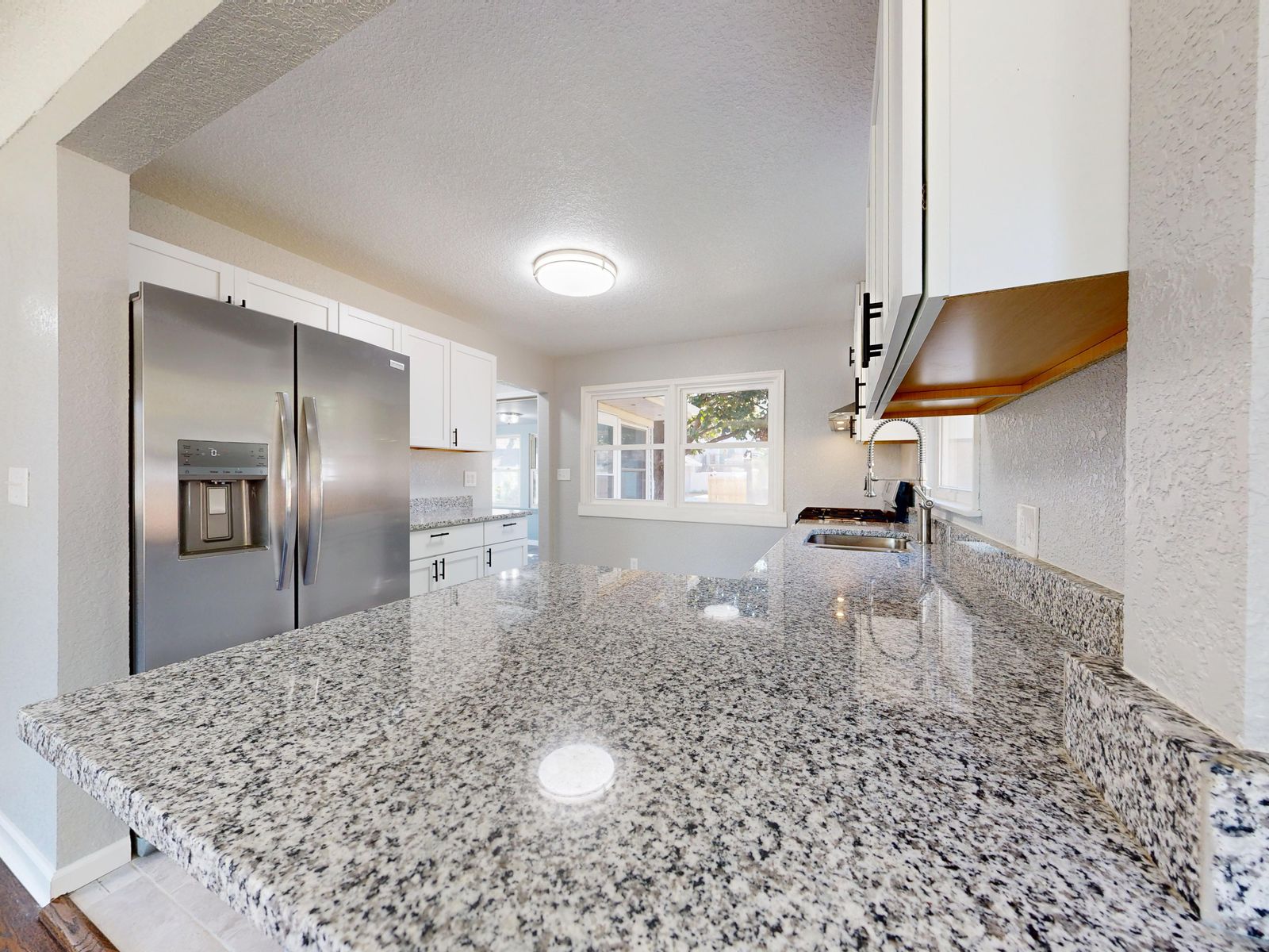 A remodeled kitchen with an island and pendant lights