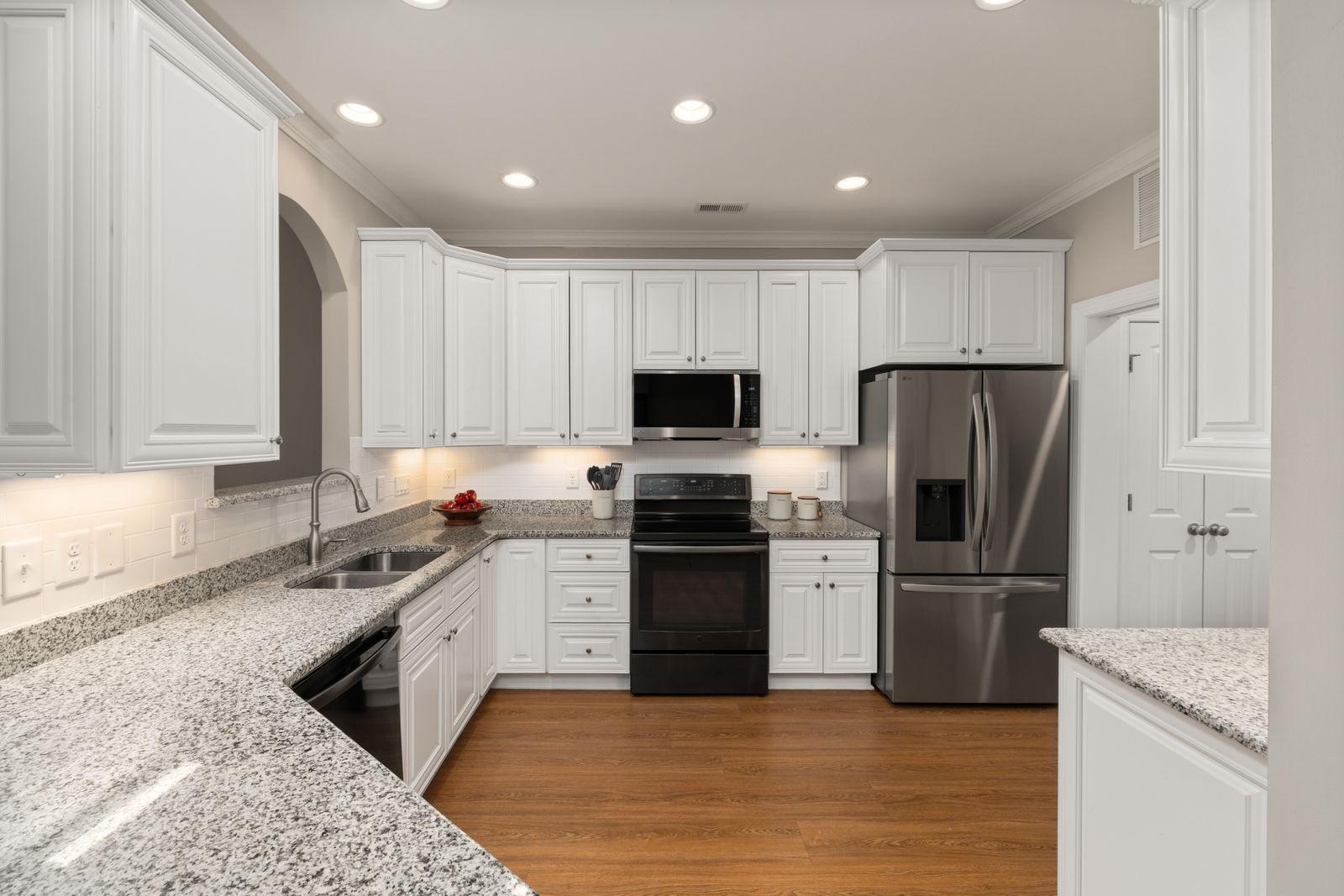 A finished kitchen with white oak cabinetry and stone counters